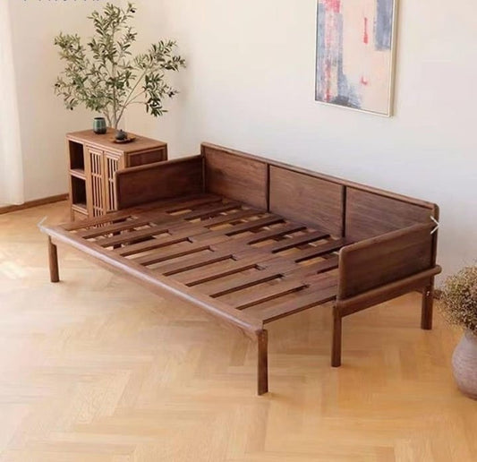 Wooden bed frame in a room with a plant and small table.