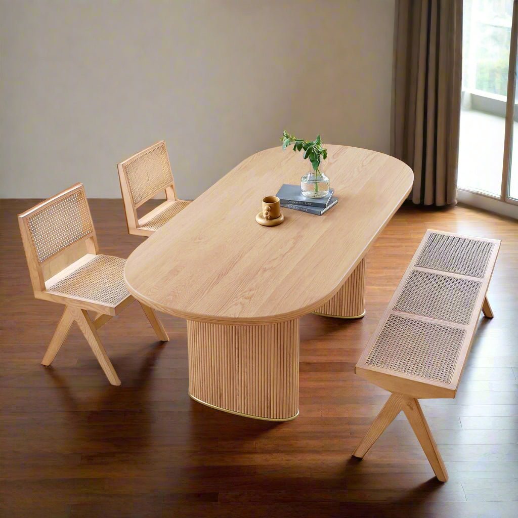Wooden dining table with chairs and a bench in a room with white walls and wooden flooring.