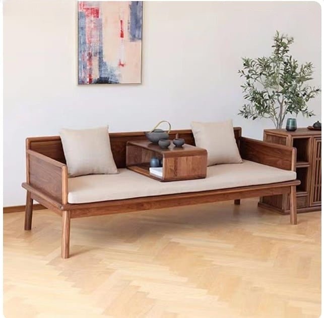 Wooden sofa with beige cushions in a room with a painting and plant on the wall.